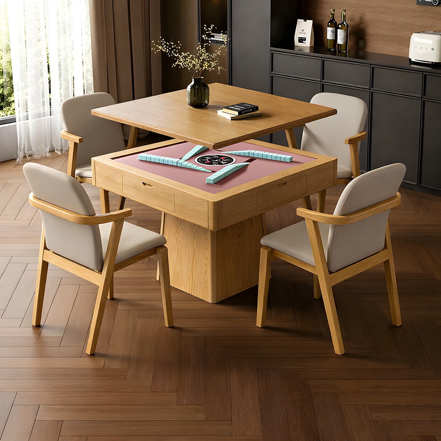 A modern, automatic mahjong dining table in light wood with a pink playing surface, featuring an integrated automatic tile mechanism with stacked walls. It is surrounded by four matching mid-century modern style beige upholstered dining chairs. The set is positioned on a dark wood herringbone floor, in a stylish dining or lounge room with a cabinet and window in the background.